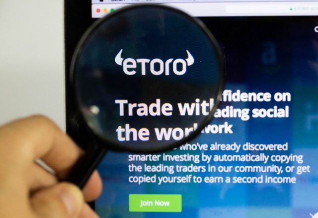 Etoro logo on a computer screen with a magnifying glass